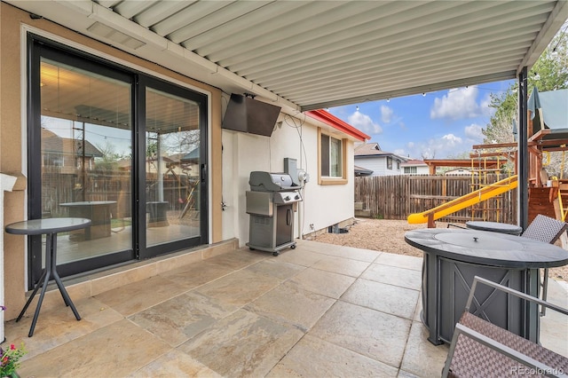 view of patio / terrace featuring a playground, fence, and a grill