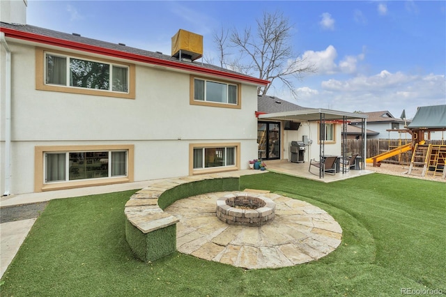 back of property with a patio area, fence, a playground, a fire pit, and stucco siding