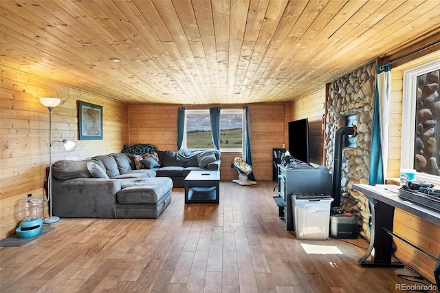 living room with hardwood / wood-style flooring, wood walls, wooden ceiling, and a wood stove