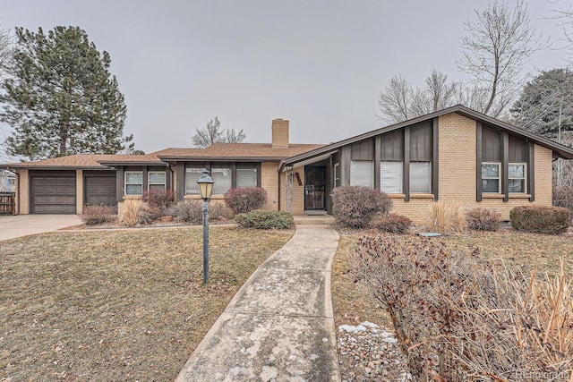 view of front of property with an attached garage, a chimney, a front lawn, and brick siding