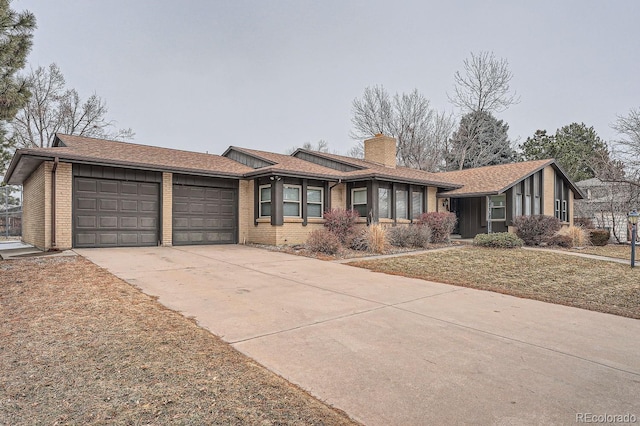 ranch-style home featuring a garage, concrete driveway, a chimney, a front lawn, and brick siding