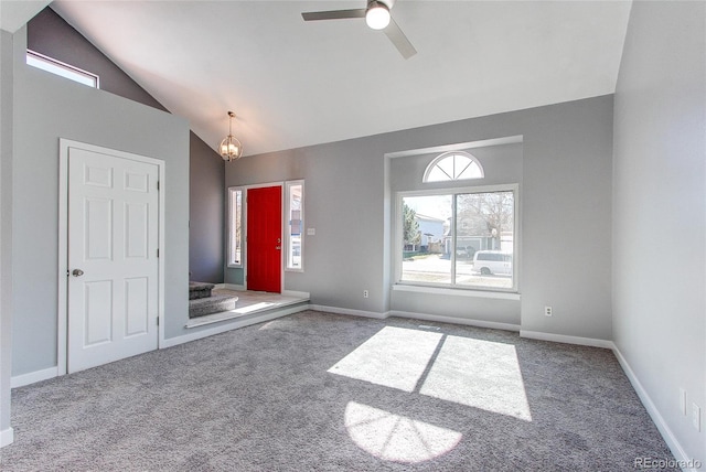 carpeted spare room with ceiling fan with notable chandelier and vaulted ceiling