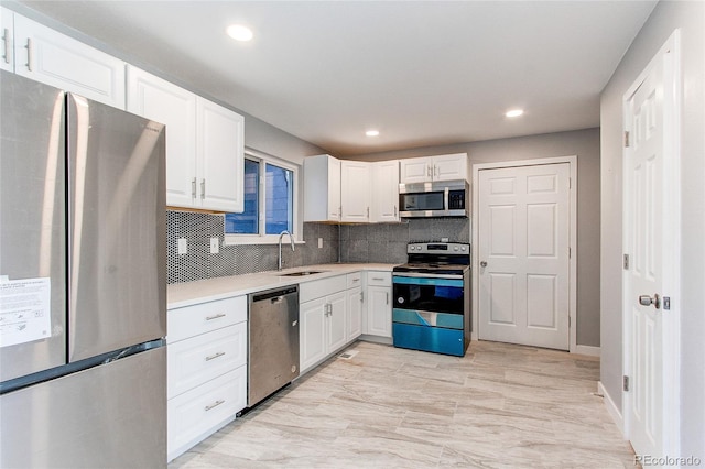 kitchen with white cabinets, appliances with stainless steel finishes, decorative backsplash, and sink