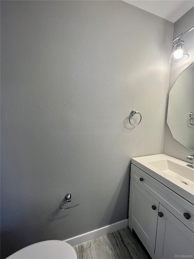 bathroom with toilet, hardwood / wood-style flooring, and vanity