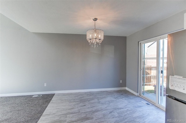 carpeted spare room featuring a chandelier