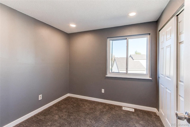 unfurnished room featuring a textured ceiling and carpet