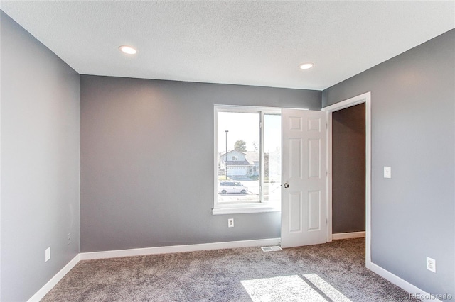 empty room with carpet flooring and a textured ceiling