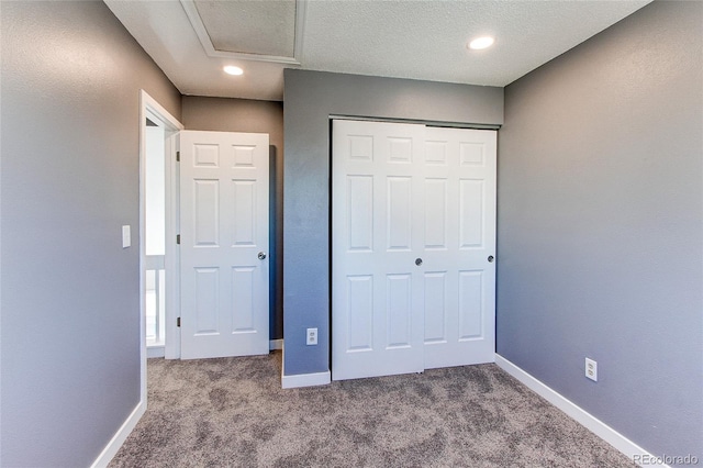 unfurnished bedroom with a textured ceiling, a closet, and carpet floors