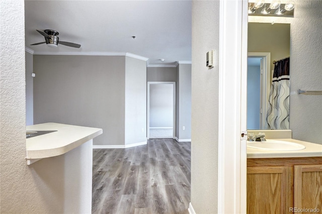 bathroom featuring wood-type flooring, vanity, ceiling fan, and crown molding