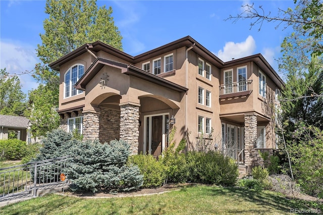 view of front of house with a balcony, stucco siding, and stone siding