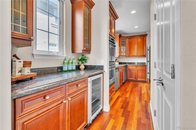 kitchen featuring brown cabinetry, wine cooler, glass insert cabinets, recessed lighting, and light wood-style flooring