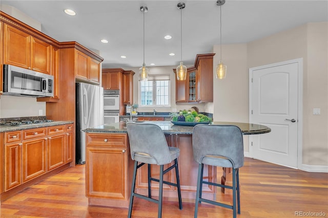 kitchen with light wood-style floors, a breakfast bar area, stainless steel appliances, and brown cabinets