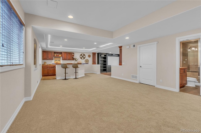 unfurnished living room with light colored carpet, recessed lighting, and wet bar