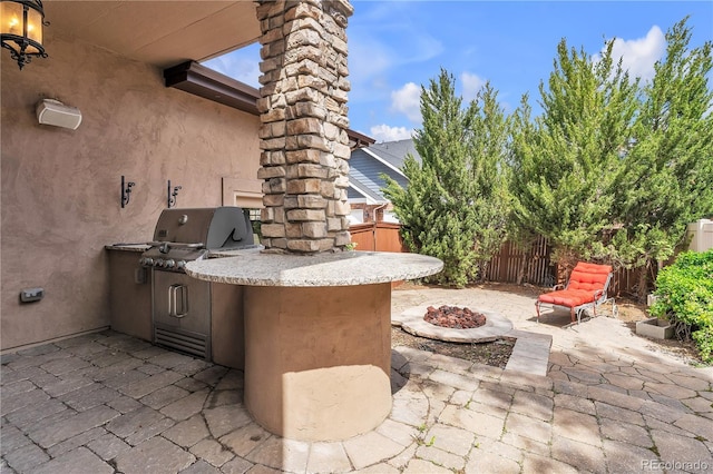 view of patio / terrace with an outdoor fire pit, fence, and an outdoor kitchen
