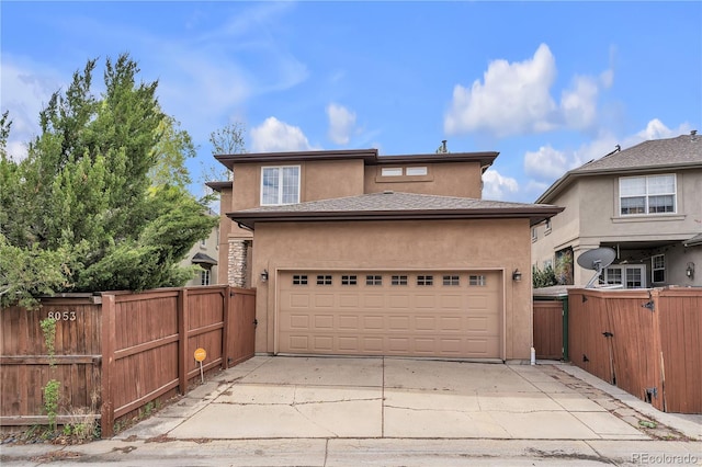 view of front of property featuring a garage, stucco siding, driveway, and fence