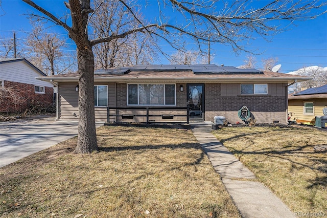 ranch-style home with crawl space, roof mounted solar panels, a front lawn, and brick siding