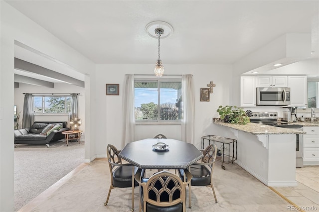 dining space with light colored carpet, baseboards, and a healthy amount of sunlight