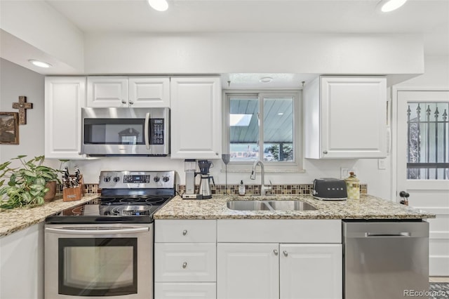 kitchen featuring a sink, white cabinets, appliances with stainless steel finishes, and light stone countertops