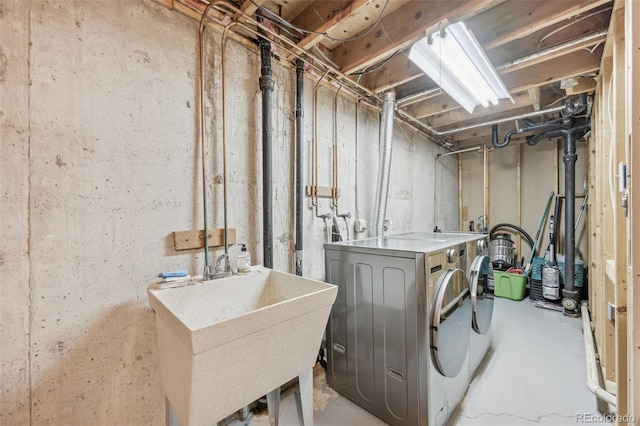 washroom featuring washing machine and dryer, laundry area, and a sink