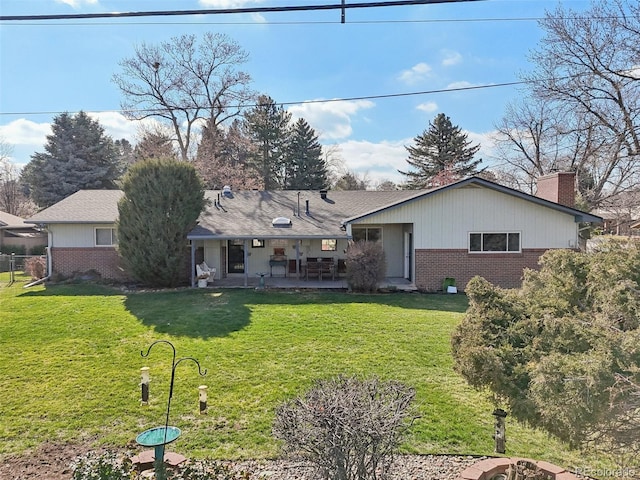 back of house with a yard, brick siding, and a patio
