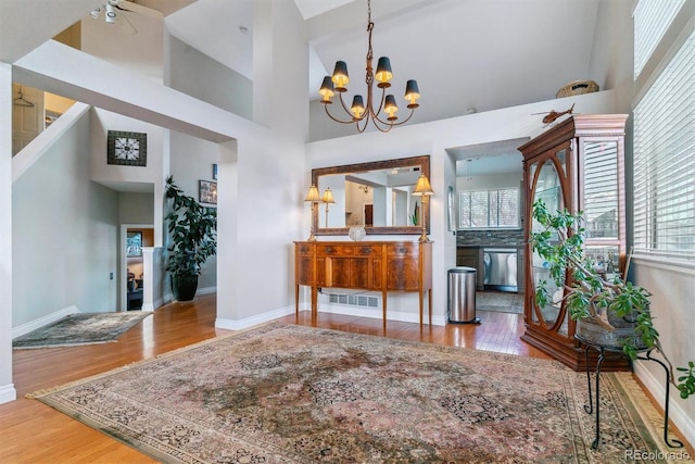 entrance foyer featuring hardwood / wood-style floors, a chandelier, and a high ceiling