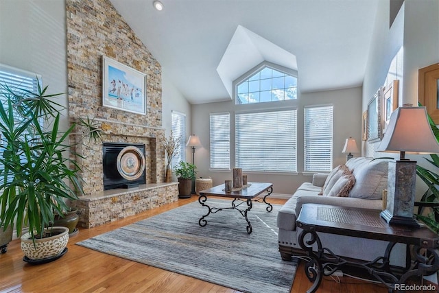 living room featuring a stone fireplace, wood-type flooring, and high vaulted ceiling