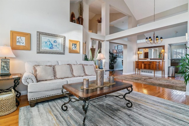 living room featuring wood-type flooring, a towering ceiling, and an inviting chandelier