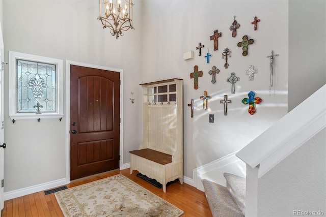 foyer entrance featuring an inviting chandelier, a towering ceiling, and light hardwood / wood-style floors