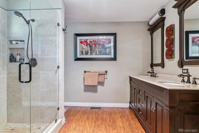 bathroom with hardwood / wood-style flooring, vanity, and a shower with door