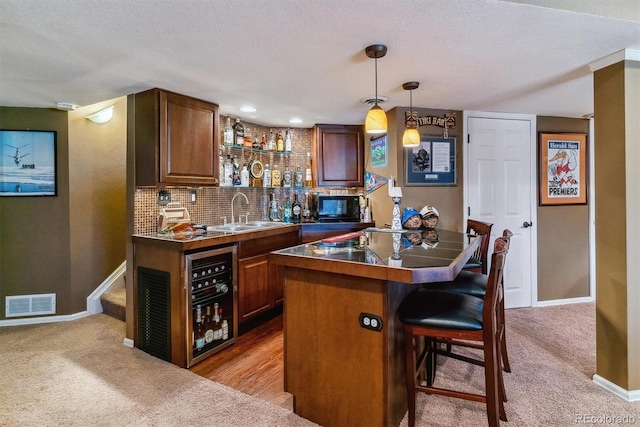 bar featuring pendant lighting, sink, carpet floors, decorative backsplash, and beverage cooler