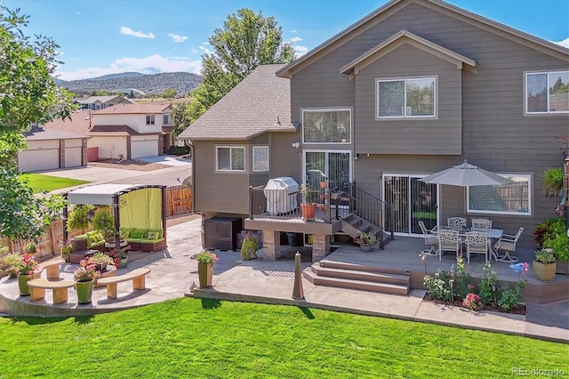 back of property with a yard, a deck with mountain view, and a patio area