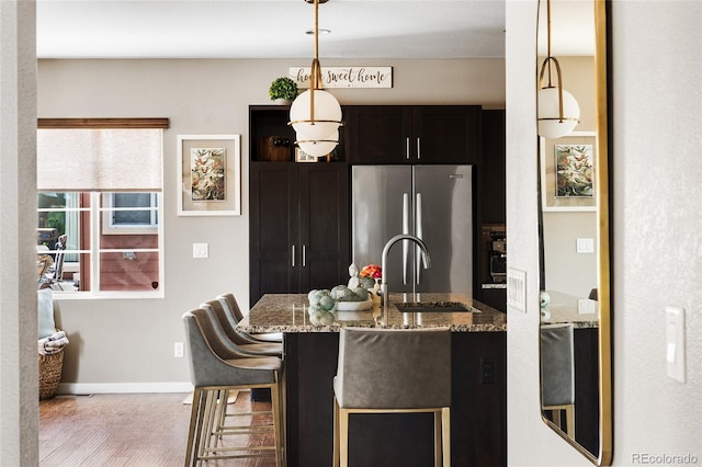 14110 Pastel Ln, Parker, CO 80134 - kitchen with freestanding refrigerator, stone counters, pendant lighting, a breakfast bar, and wood finished floors