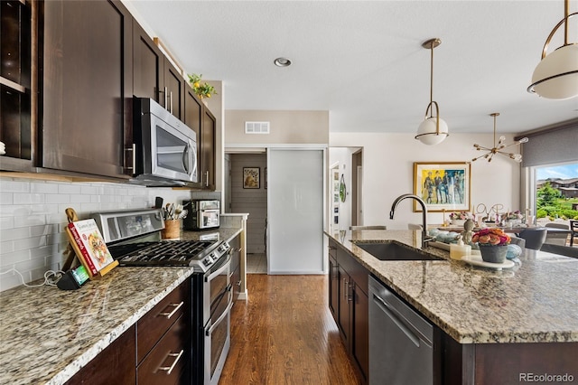 14110 Pastel Ln, Parker, CO 80134 - kitchen featuring appliances with stainless steel finishes, dark wood-style floors, backsplash, a center island with sink, and dark brown cabinetry