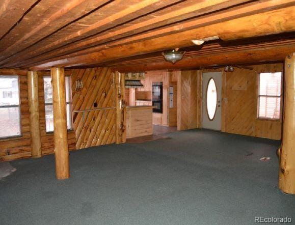 unfurnished living room with carpet floors and wooden walls