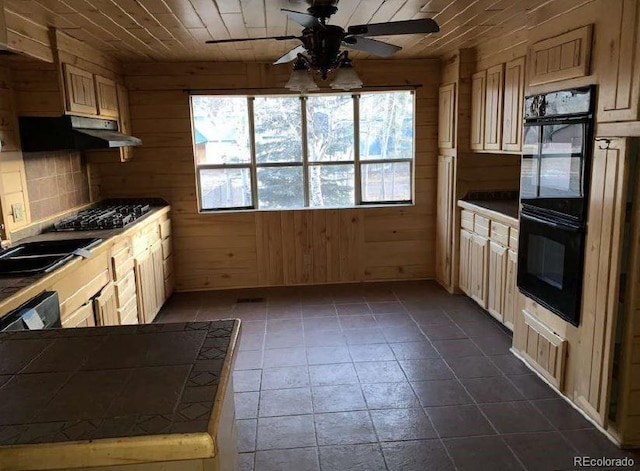 kitchen featuring tile counters, wooden ceiling, stainless steel gas cooktop, wood walls, and black double oven