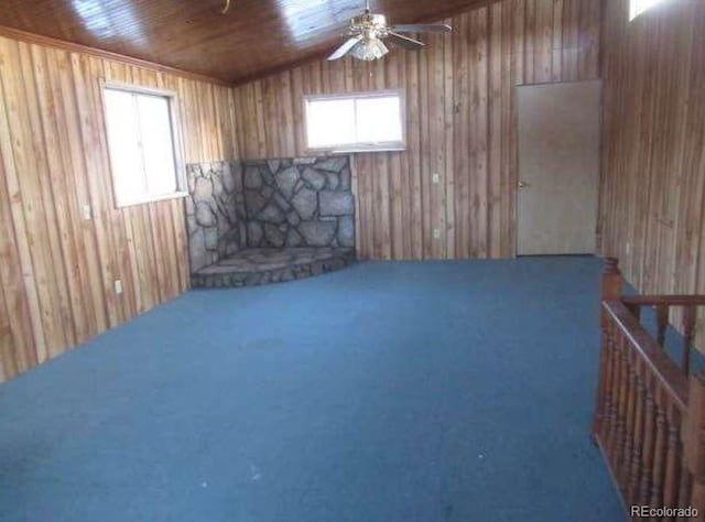 interior space with carpet floors, wood walls, ceiling fan, and wooden ceiling