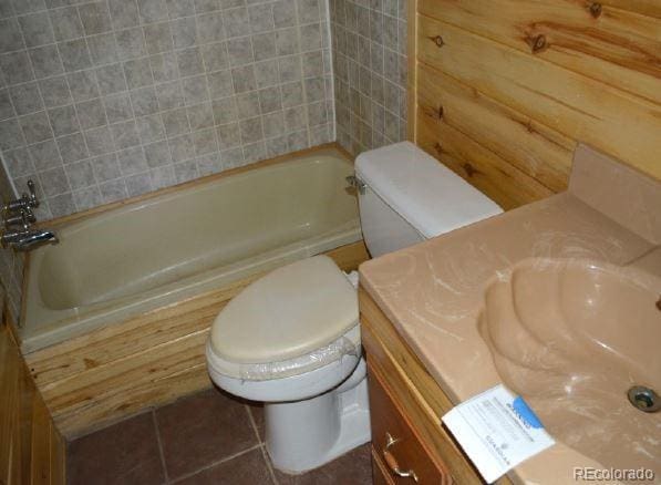 bathroom featuring tile patterned floors, vanity, a bath, and toilet