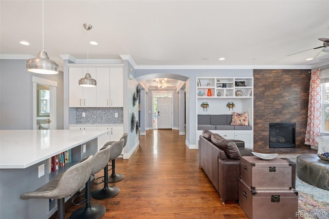 2746 Geneva St, Denver, CO 80238 - living area with arched walkways, healthy amount of natural light, ceiling fan, crown molding, and dark wood-type flooring