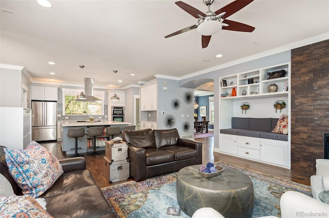 2746 Geneva St, Denver, CO 80238 - living room featuring dark wood finished floors, crown molding, arched walkways, healthy amount of natural light, and ceiling fan