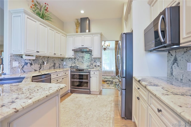 19249 E Progress Ave, Centennial, CO 80015 - kitchen with stainless steel appliances, under cabinet range hood, light stone countertops, decorative backsplash, and light wood finished floors