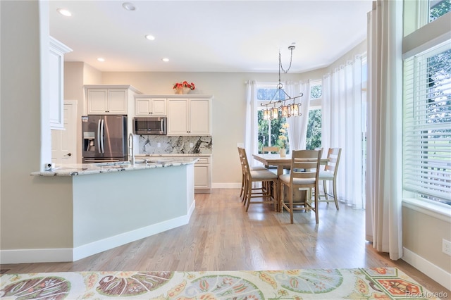 19249 E Progress Ave, Centennial, CO 80015 - kitchen featuring stainless steel appliances, white cabinets, light stone countertops, light wood-style floors, and recessed lighting