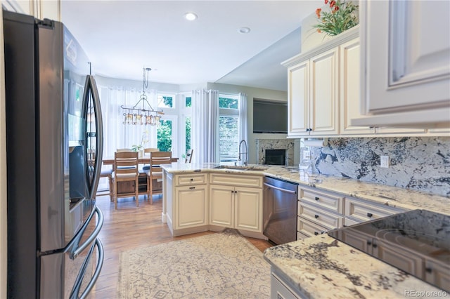 19249 E Progress Ave, Centennial, CO 80015 - kitchen with appliances with stainless steel finishes, a peninsula, a chandelier, light wood finished floors, and a fireplace