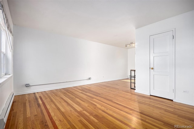 2856 Jasmine St, Denver, CO 80207 - empty room with a baseboard heating unit, light wood-type flooring, track lighting, and baseboards