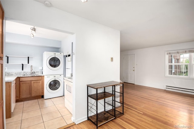2856 Jasmine St, Denver, CO 80207 - washroom with stacked washer and clothes dryer, a baseboard heating unit, and light wood-style floors