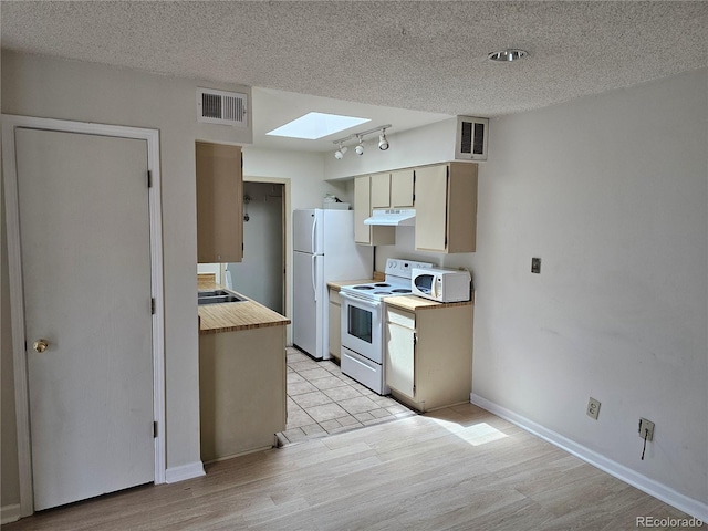 kitchen with white appliances, a skylight, a textured ceiling, light hardwood / wood-style floors, and rail lighting