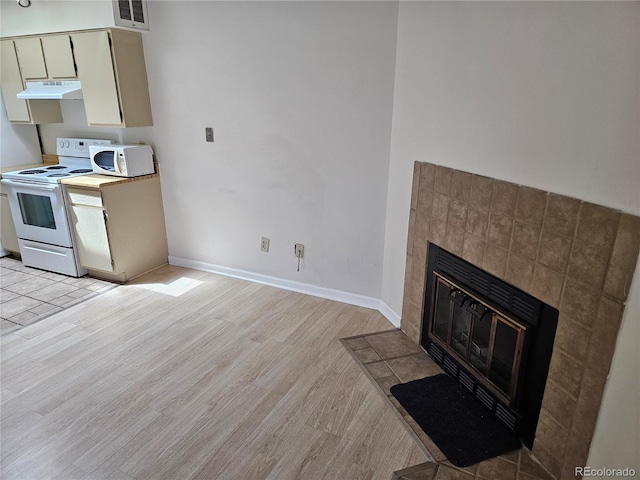 kitchen featuring white appliances, light hardwood / wood-style floors, and a tile fireplace