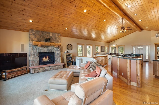 carpeted living room featuring lofted ceiling with beams, ceiling fan, a fireplace, and wood ceiling