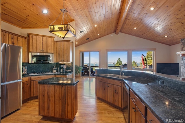 kitchen featuring beamed ceiling, a center island, decorative light fixtures, plenty of natural light, and stainless steel appliances