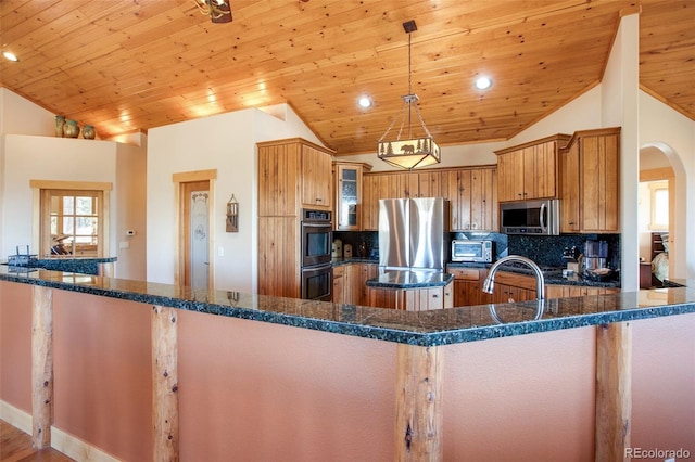 kitchen featuring hanging light fixtures, tasteful backsplash, stainless steel appliances, and dark stone counters