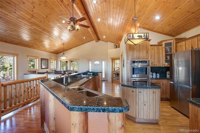 kitchen with decorative light fixtures, appliances with stainless steel finishes, a large island, beamed ceiling, and sink